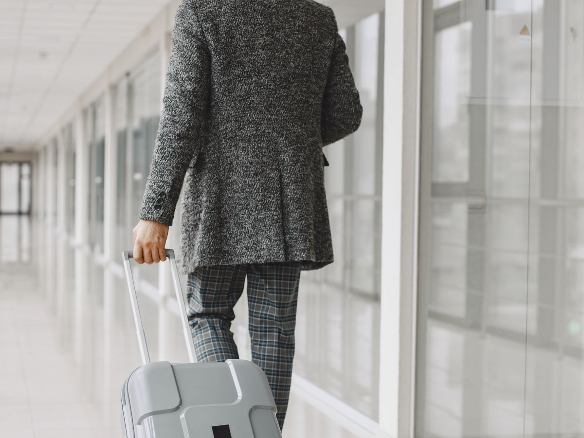 A business traveller walking through an airport terminal with luggage
